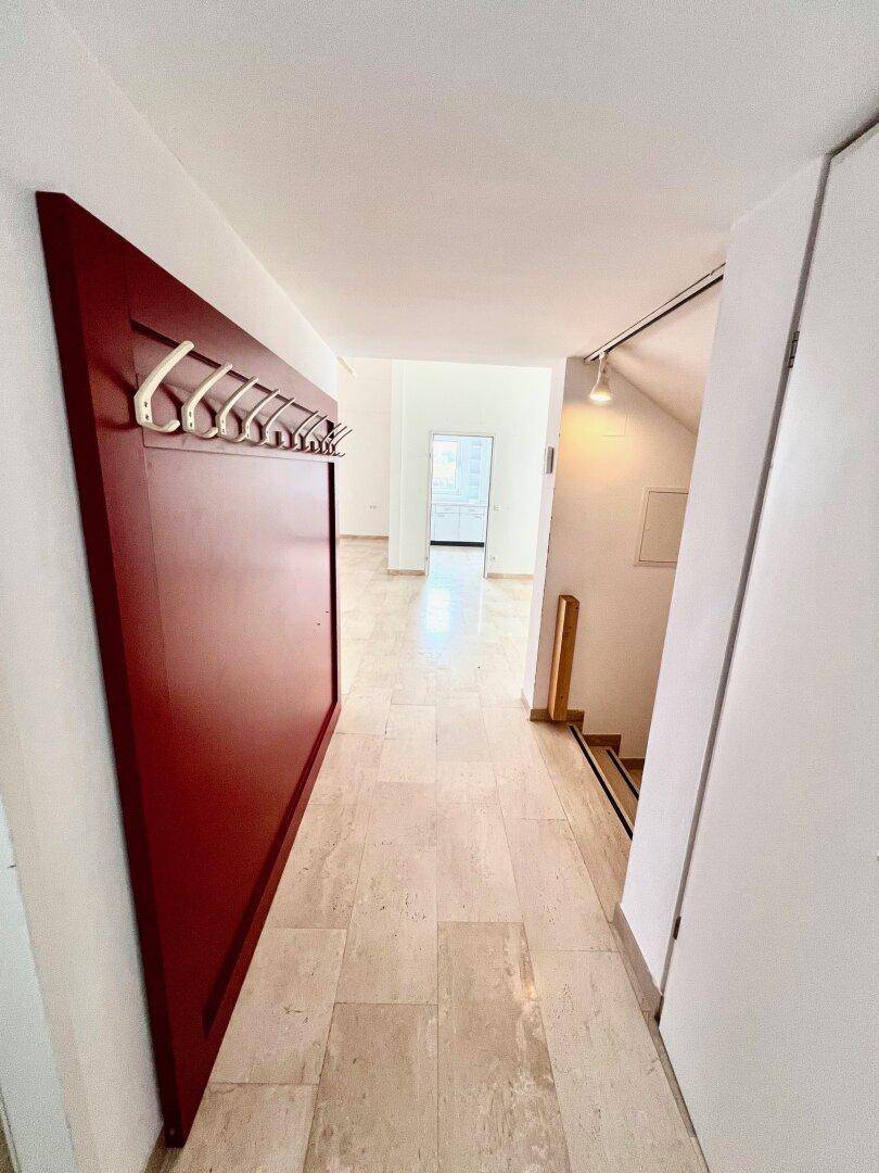 Heller Eingangsbereich mit Marmorboden und einer auffälligen roten Garderobe.
