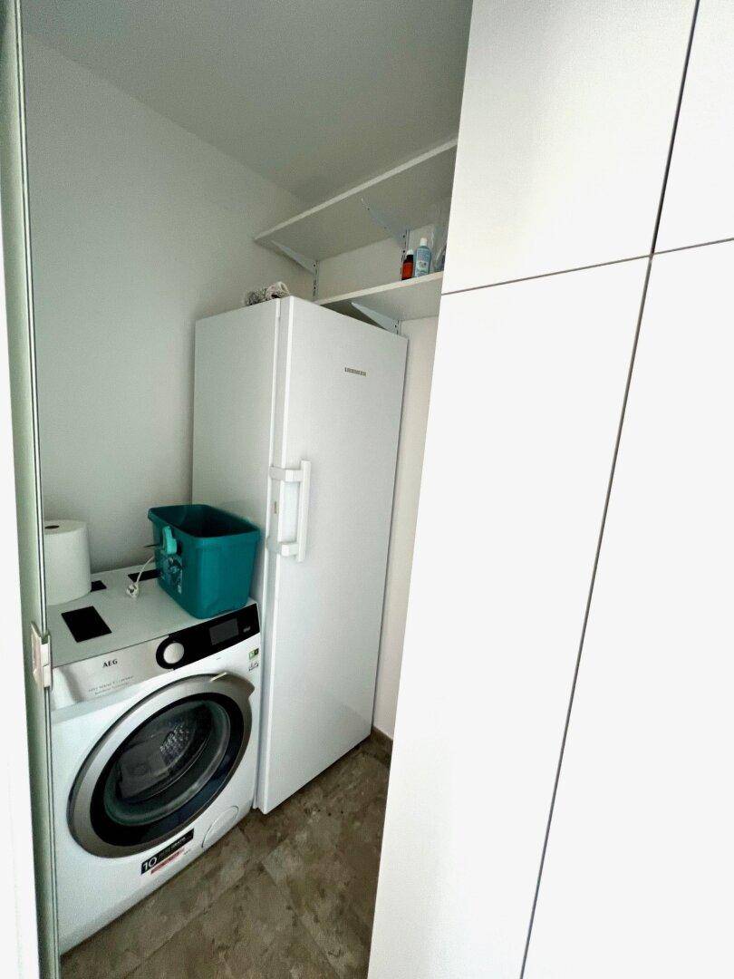 Praktischer Hauswirtschaftsraum mit Waschmaschine, Kühlschrank und zusätzlichem Stauraum.