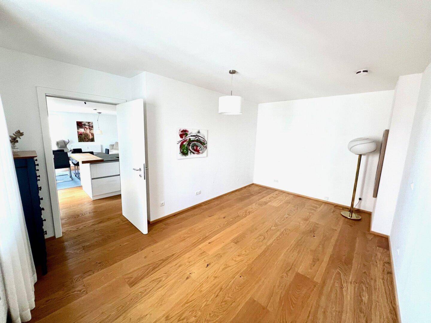 Helles Zimmer mit Holzboden und Zugang zum offenen Wohnbereich, vielseitig nutzbar.