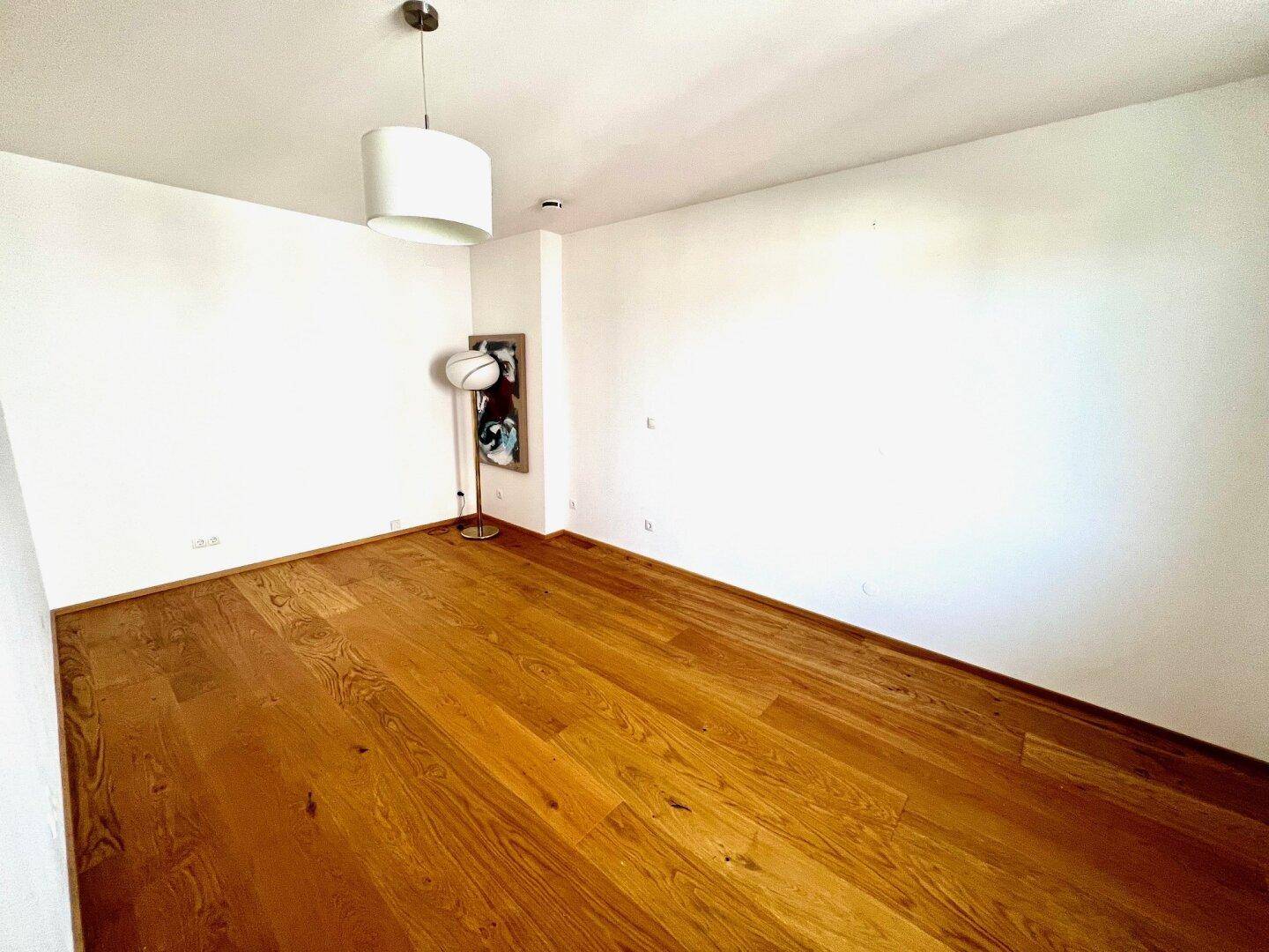 Ruhiges Zimmer mit Holzboden und Fenster, ideal als Kinderzimmer oder Gästezimmer.