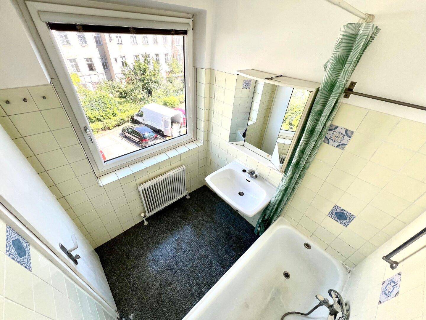 Badezimmer mit Badewanne, Waschbecken und einem Fenster, das viel Tageslicht hereinlässt.