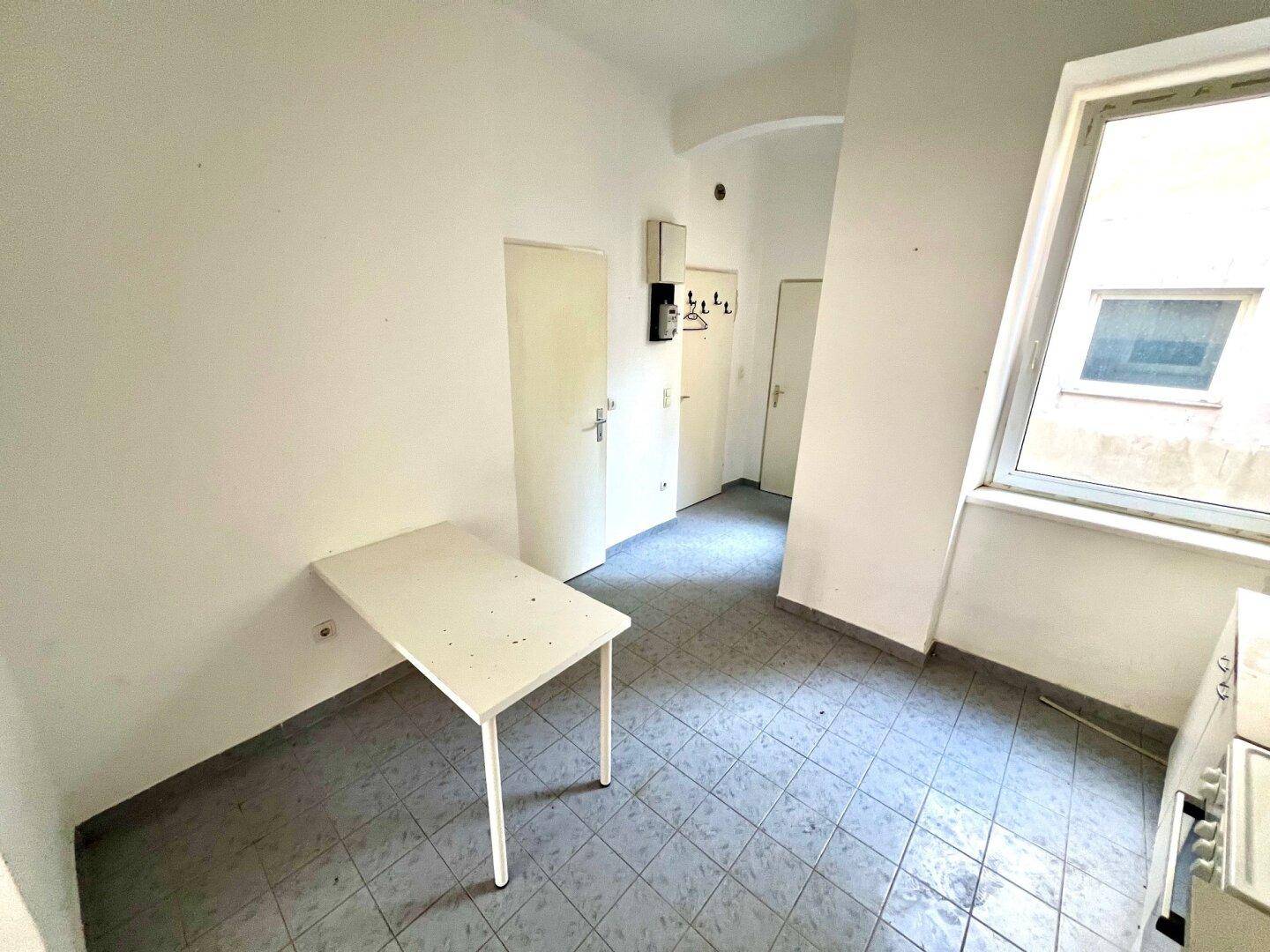 Kleine Küche mit Essbereich, blauen Fliesen und Zugang zum Flur, ideal für kompaktes Wohnen.