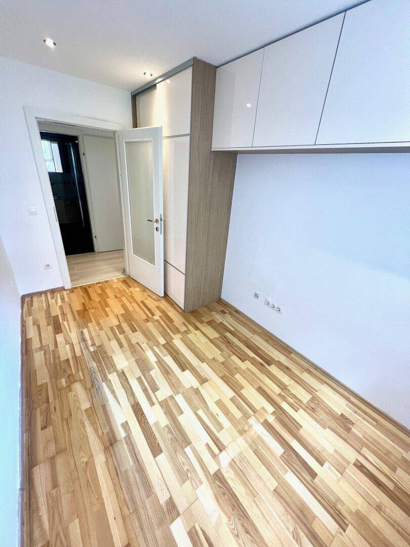 Schlafzimmer mit hellem Parkettboden und praktischen Einbauschränken, die viel Stauraum bieten.