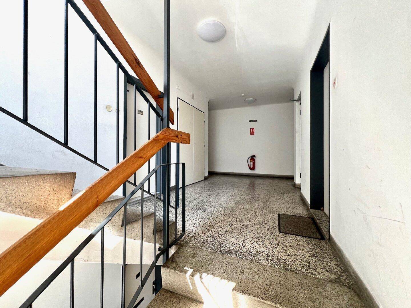 Heller Hausflur mit Terrazzoboden und Zugang zu den einzelnen Wohneinheiten.