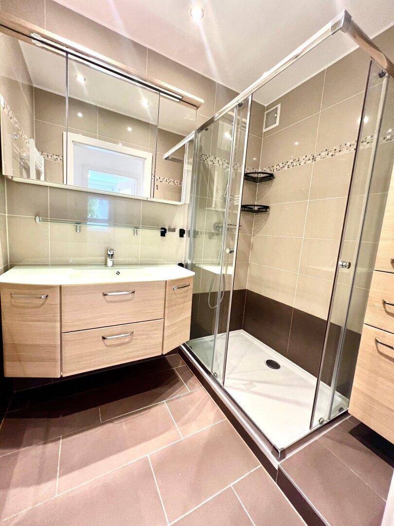 Modernes Badezimmer mit begehbarer Dusche, Waschtisch mit Einzelwaschbecken und Spiegelschrank.