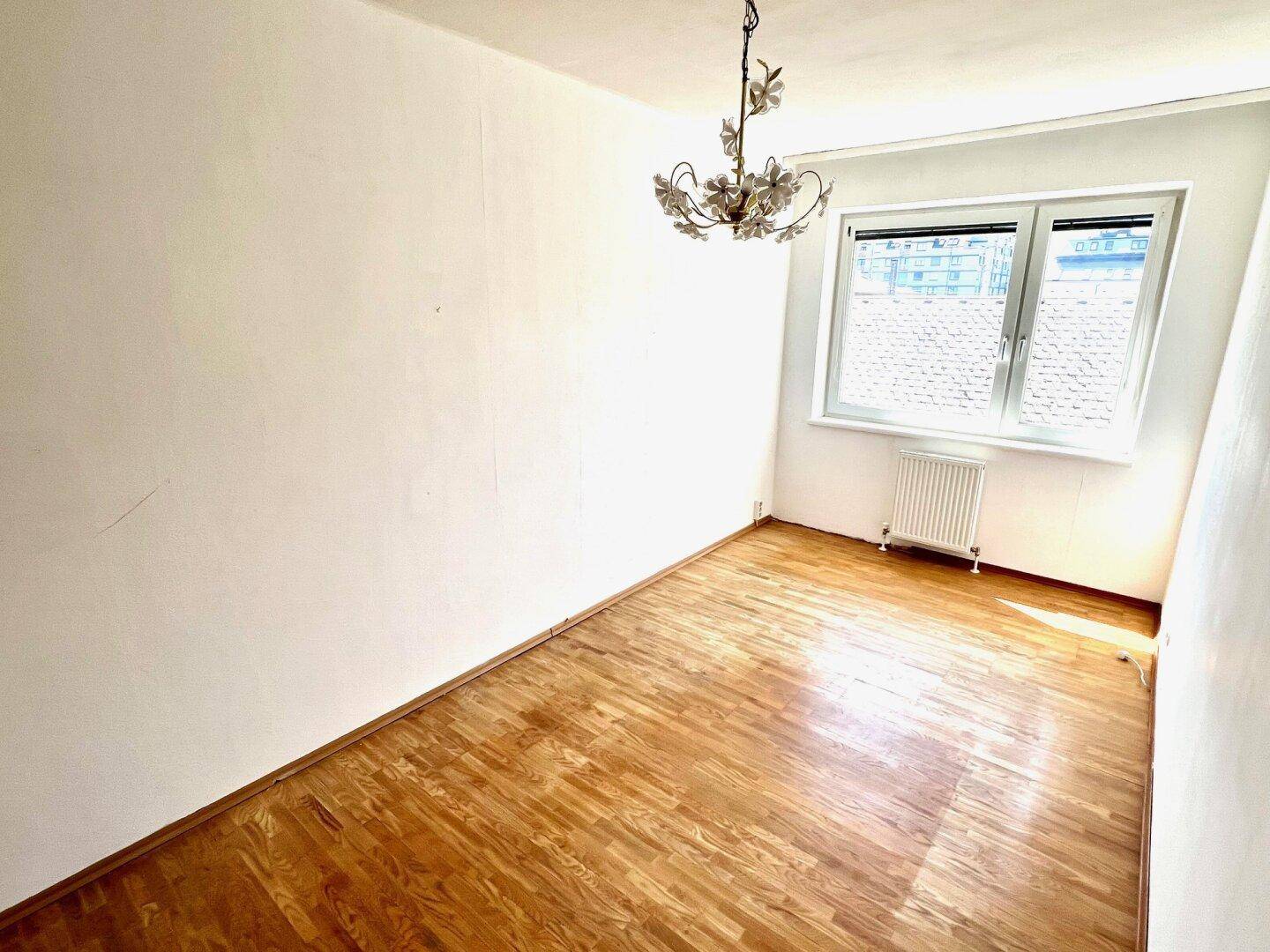 Helles Zimmer mit Parkettboden und Fenster, geeignet als Schlaf- oder Arbeitszimmer.