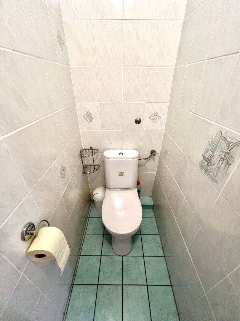 Kleines separates WC mit hellen Fliesen und einem kompakten Design.