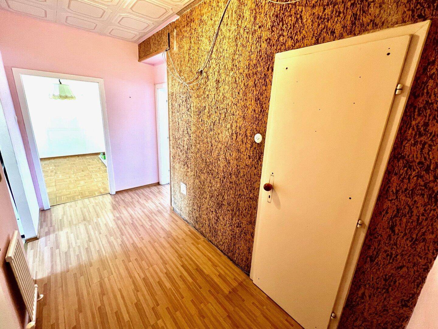 Flur mit Parkettboden und einer auffälligen Wandverkleidung, die zu weiteren Räumen führt.