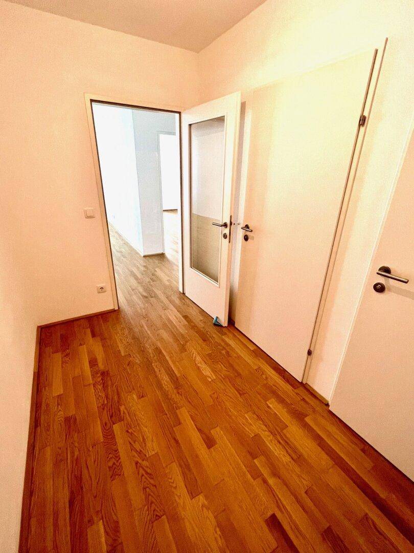 Heller Flur mit Parkettboden und Türen zu verschiedenen Räumen der Wohnung.
