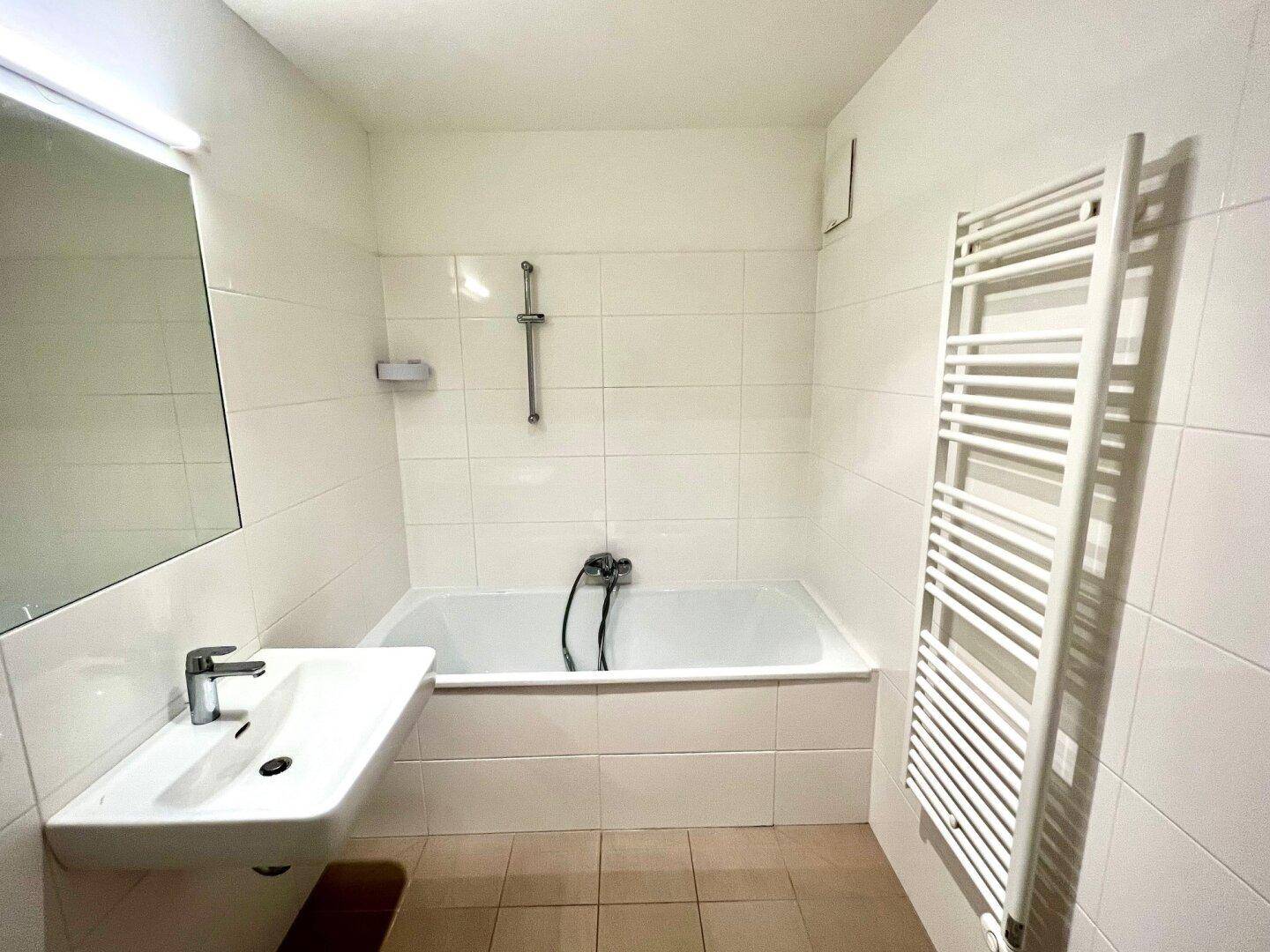 Modernes Badezimmer mit Badewanne, Waschbecken und beheiztem Handtuchhalter.