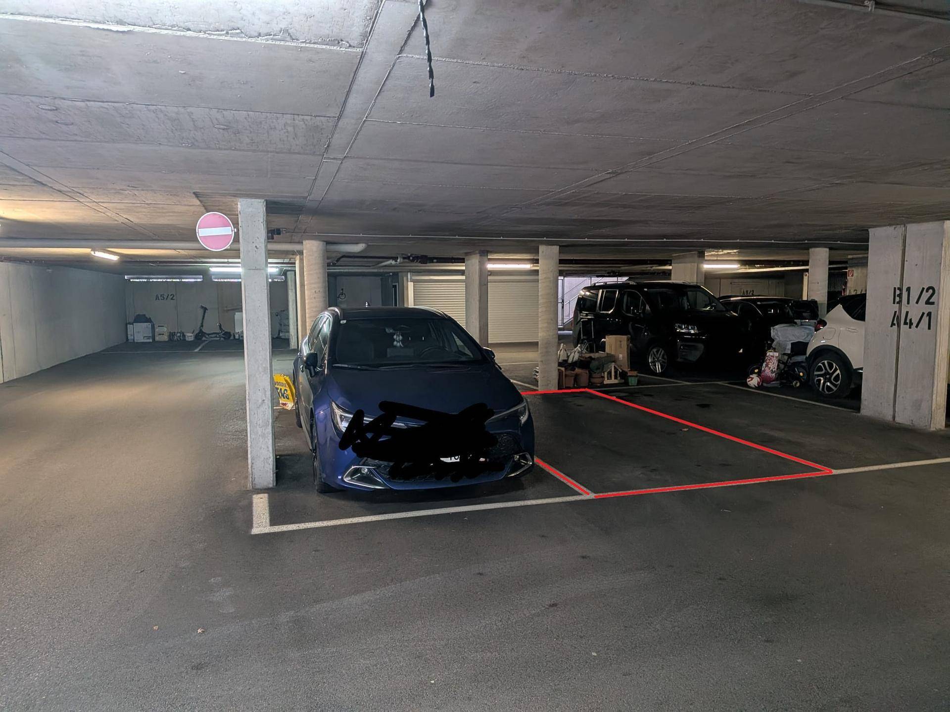 Tiefgarage mit mehreren Fahrzeugen und einem freien, markierten Stellplatz.