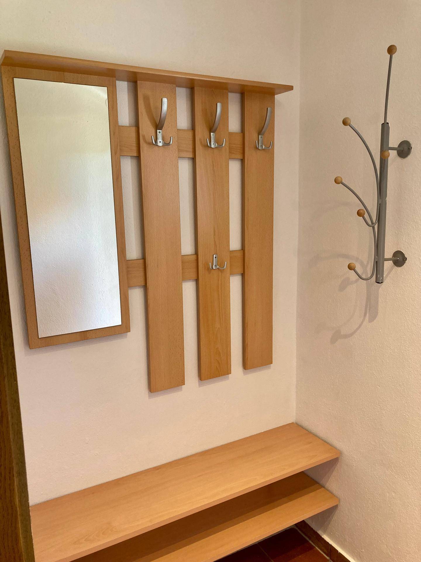Eingangsbereich mit Garderobe, Spiegel und Schuhablage in hellem Holzdesign.