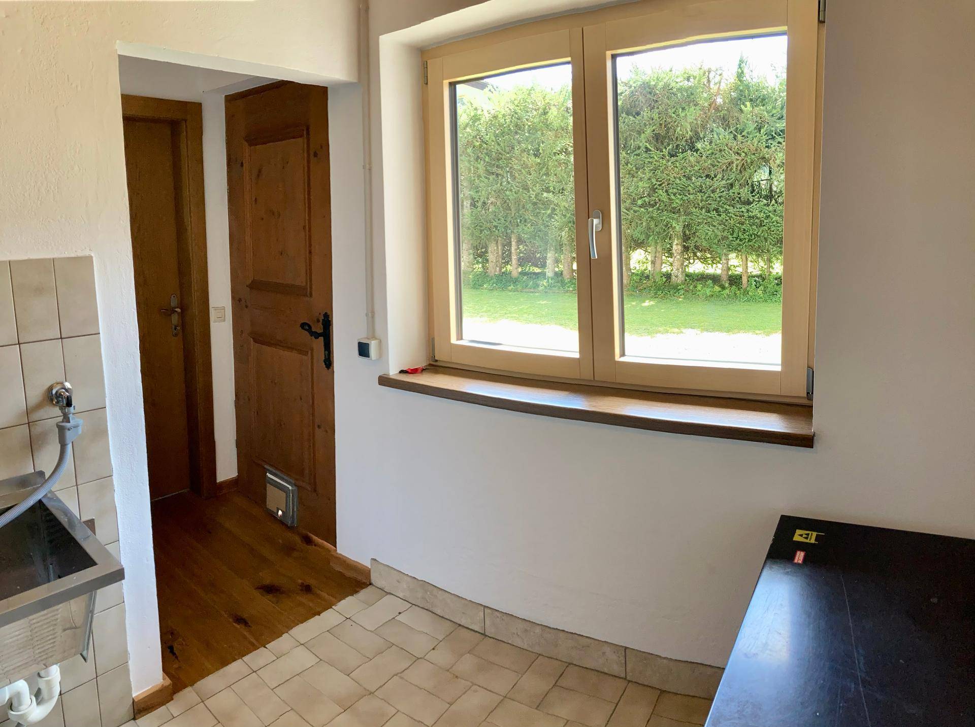 Kleiner Bereich mit Spüle, Kochfeld und Fenster mit Blick ins Grüne, ideal als Küchenzeile.