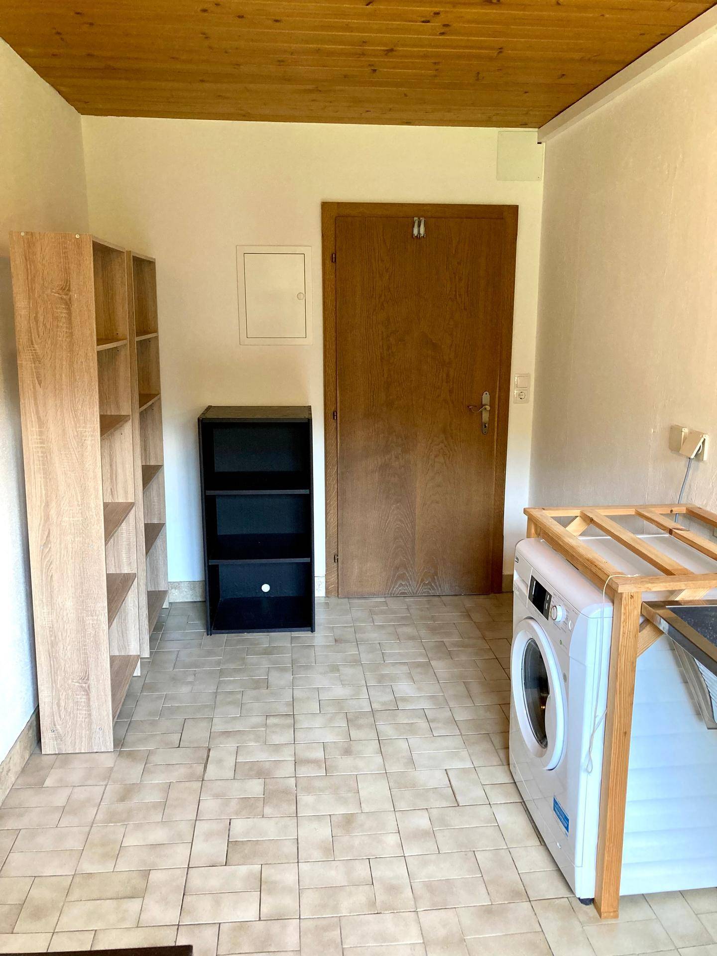 Hauswirtschaftsraum mit Waschmaschine, Regalen und Fliesenboden, praktisch und funktional.