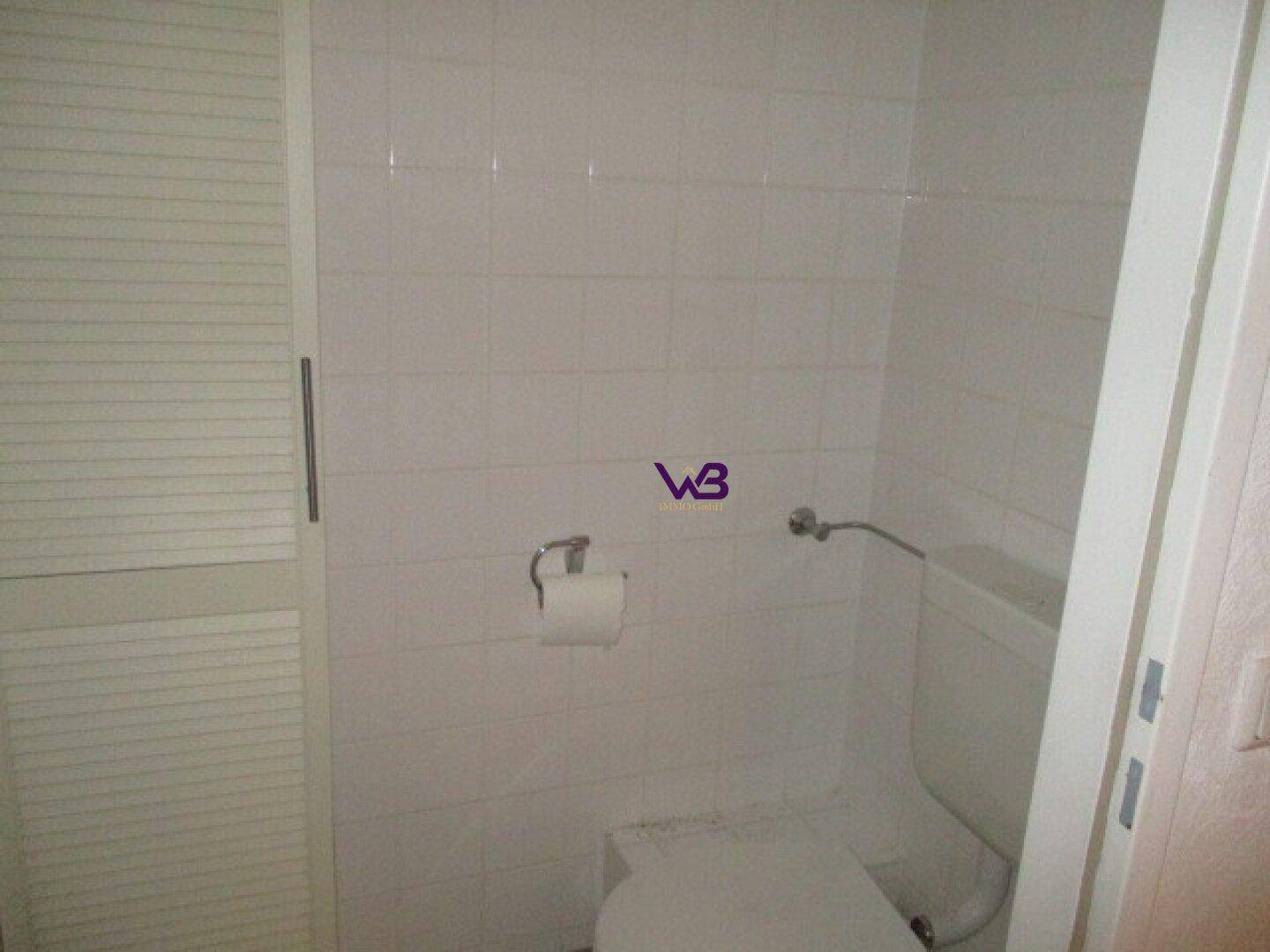 Separates WC mit Toilette und weiß gefliesten Wänden.