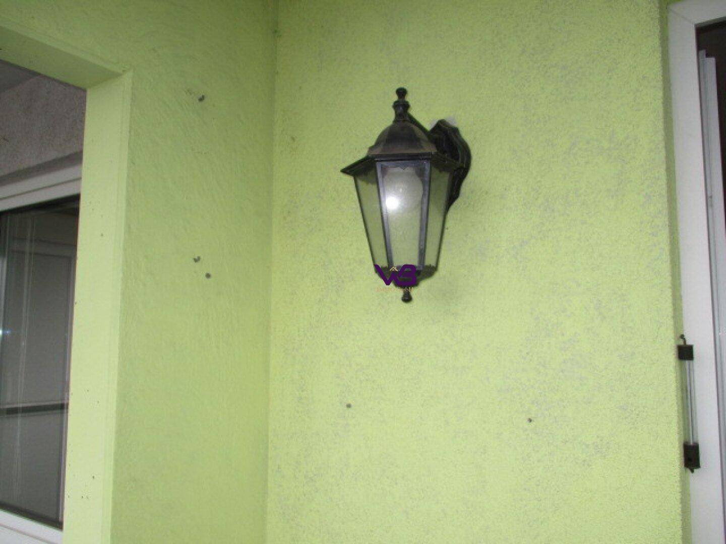 Nahaufnahme einer hellgrünen Wand auf dem Balkon mit einer Außenleuchte.