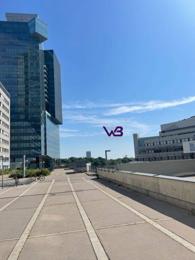 Moderne Hochhäuser und eine gepflasterte Promenade unter blauem Himmel.