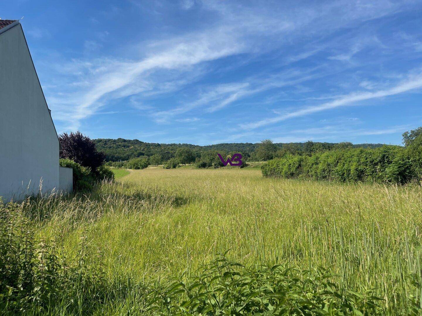 Grüne Wiese neben einem Gebäude mit weitem Blick auf die hügelige Landschaft.