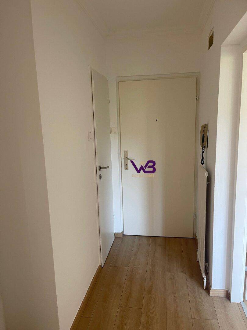 Heller Eingangsbereich mit Laminatboden, weißen Türen und Gegensprechanlage.