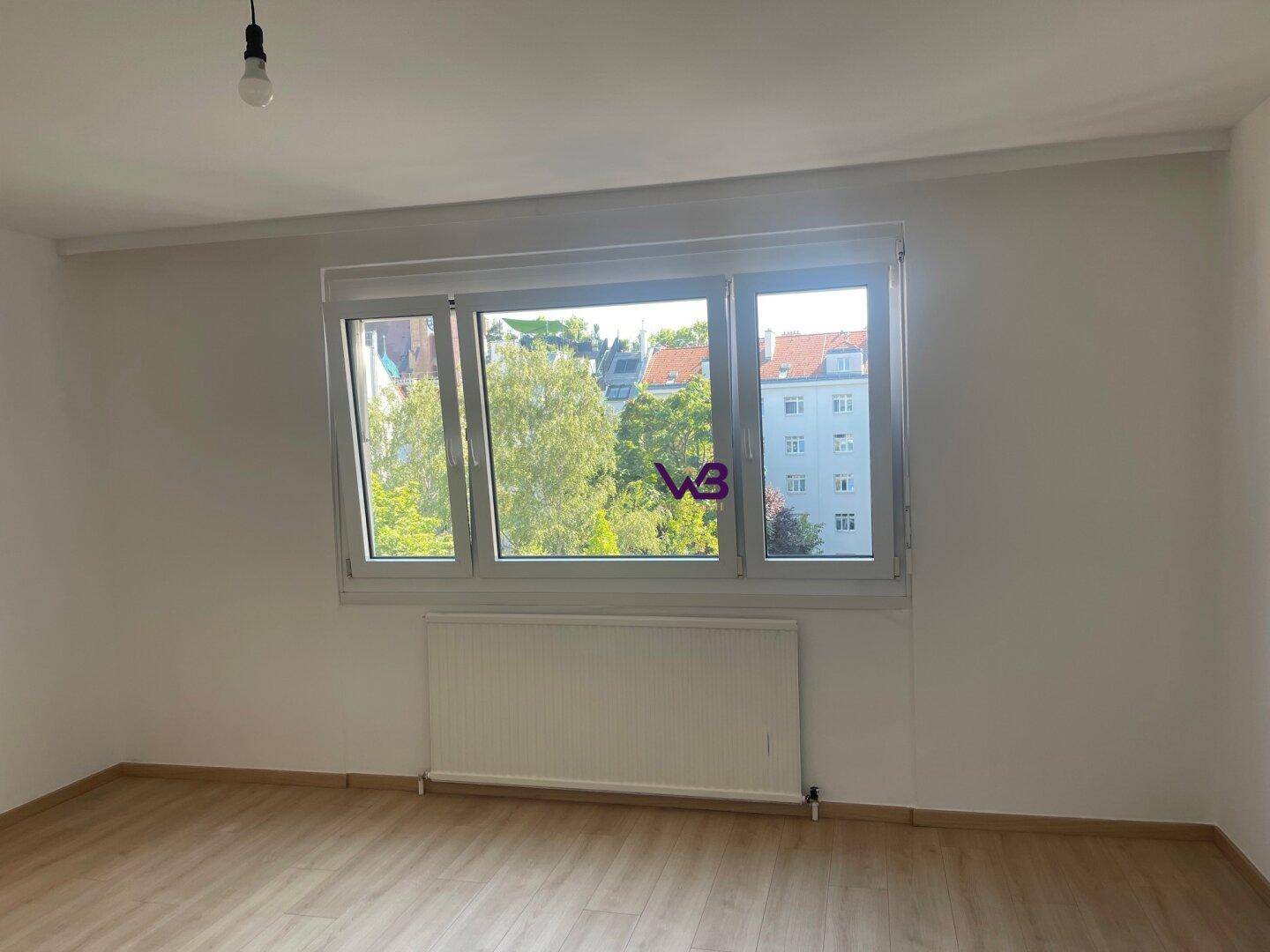 Geräumiger, unmöblierter Raum mit Laminatboden und großem Fenster für viel Helligkeit.