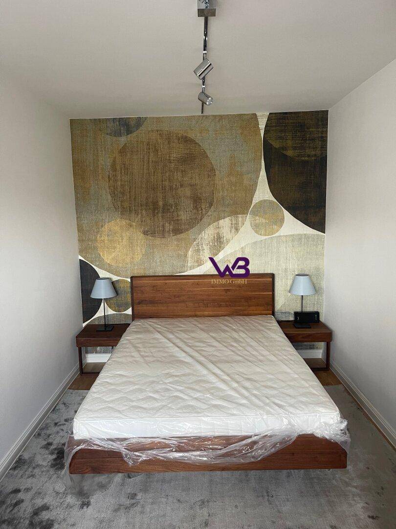 Schlafzimmer mit Doppelbett, Nachttischen und einer auffälligen, gemusterten Tapete an der Wand.