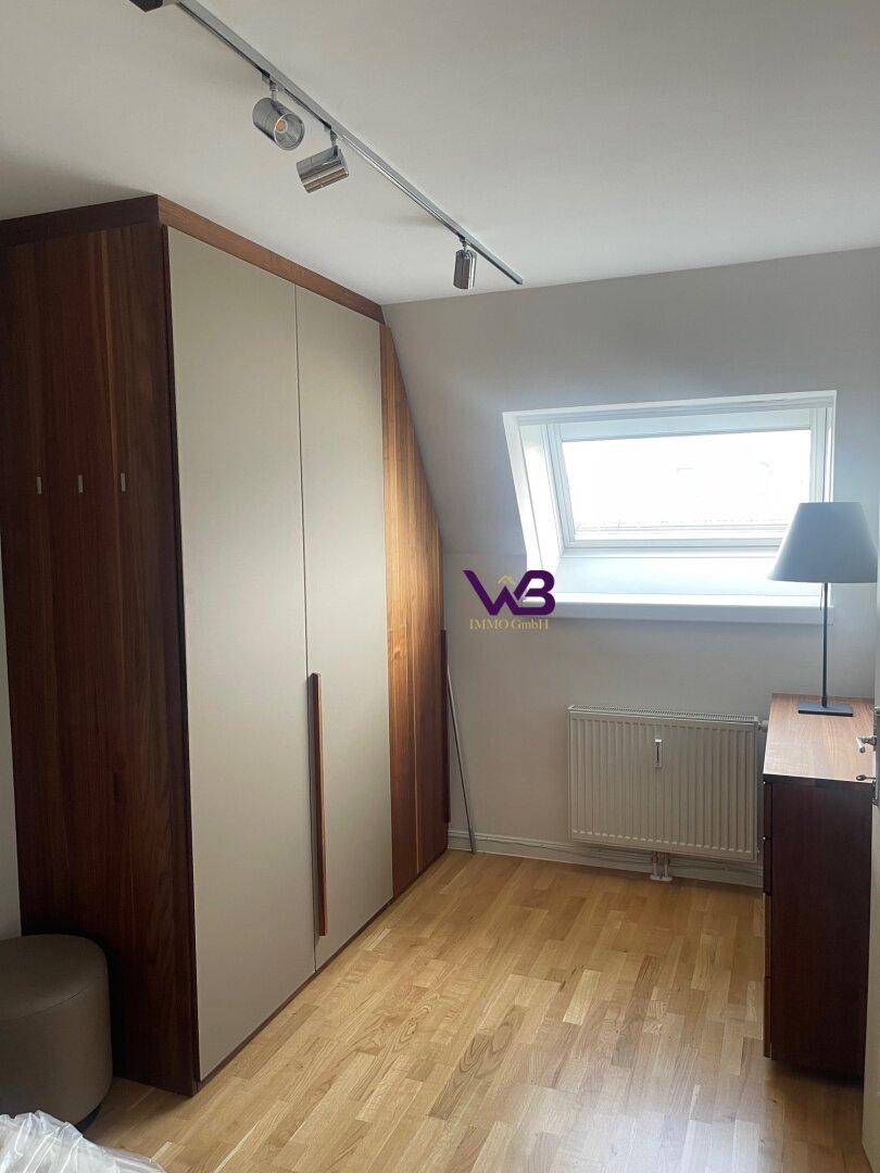 Schlafzimmer mit Einbauschränken, Holzboden und einem Dachfenster, das Tageslicht hereinlässt.