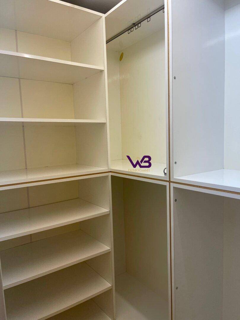 Begehbarer Kleiderschrank mit vielen Regalen und Aufhängemöglichkeiten für Kleidung.