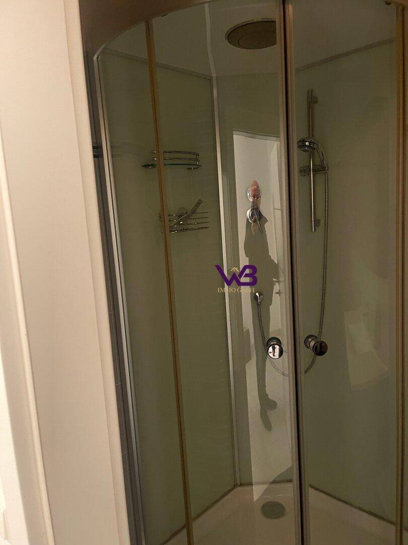 Duschkabine mit Glastüren und Duscharmatur in einem modernen Badezimmer.