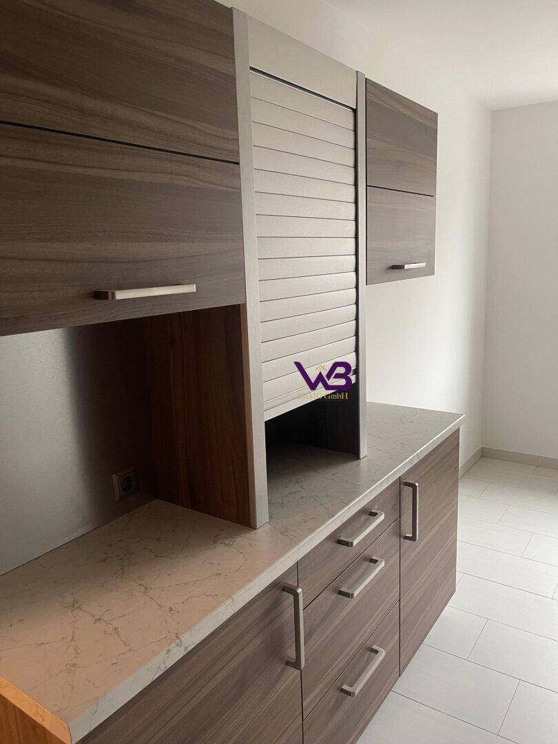 Küchenzeile mit Holzoptik-Schränken, heller Arbeitsplatte und einem Rollladenschrank.