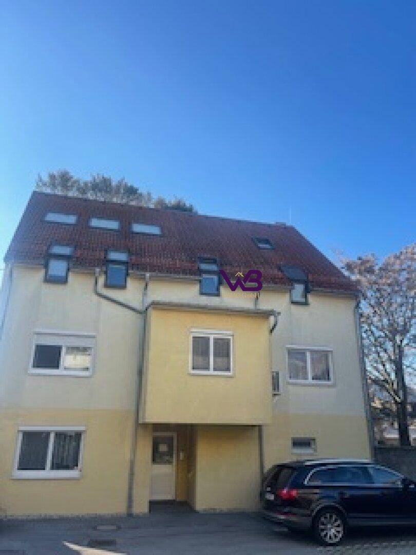 Mehrstöckiges Gebäude mit gelber Fassade, rotem Ziegeldach und vielen Dachfenstern.