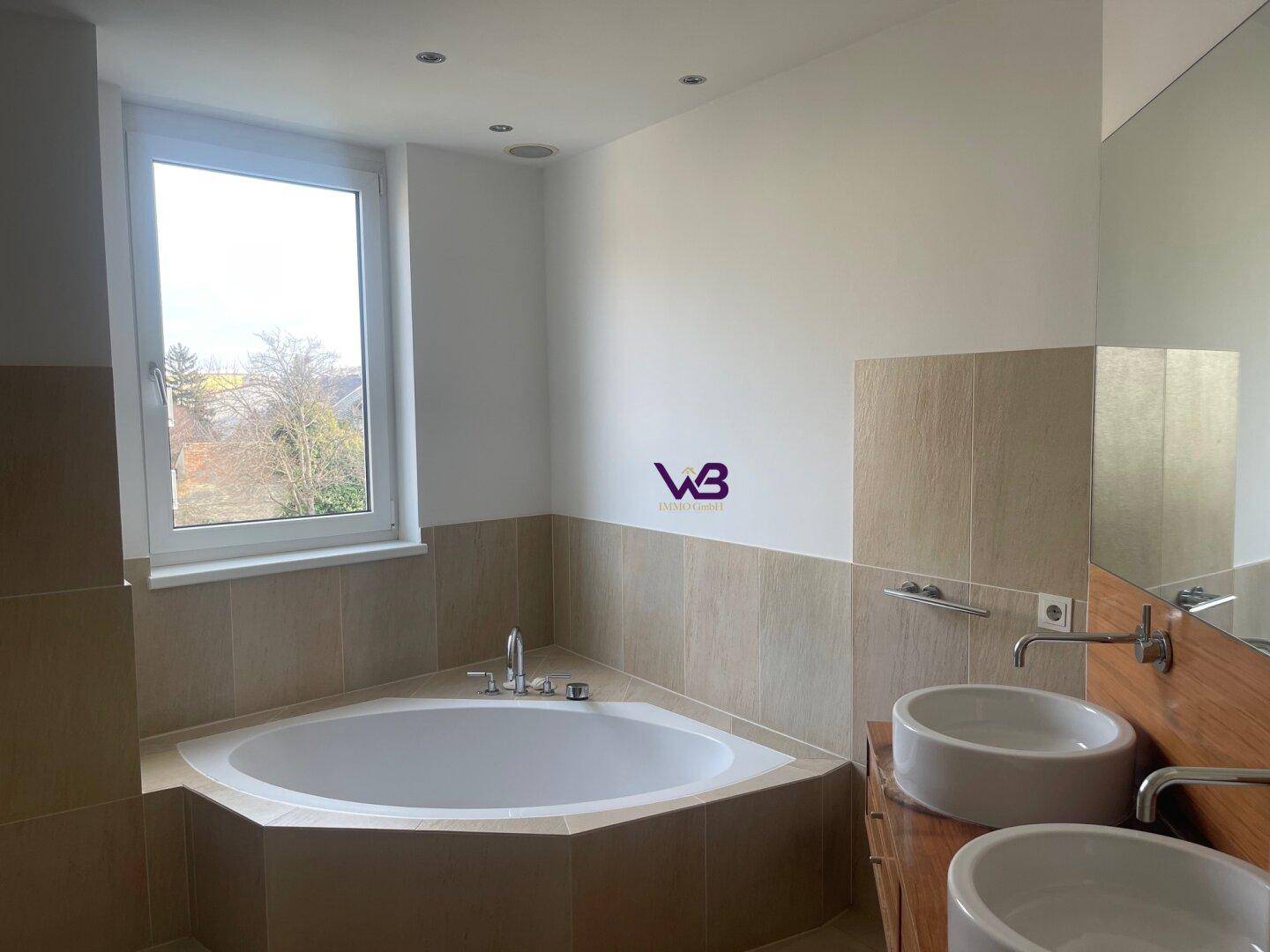 Modernes Badezimmer mit Eckbadewanne, Doppelwaschbecken und einem Fenster.