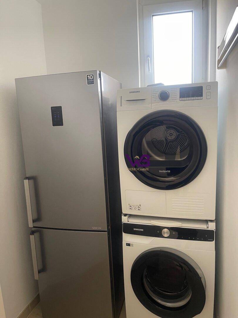 Hauswirtschaftsraum mit Kühlschrank, Waschmaschine und Trockner sowie einem Fenster.