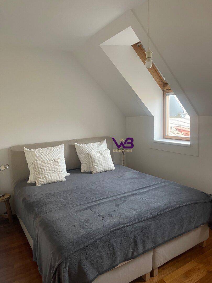Gemütliches Schlafzimmer im Dachgeschoss mit Doppelbett und Dachfenster.