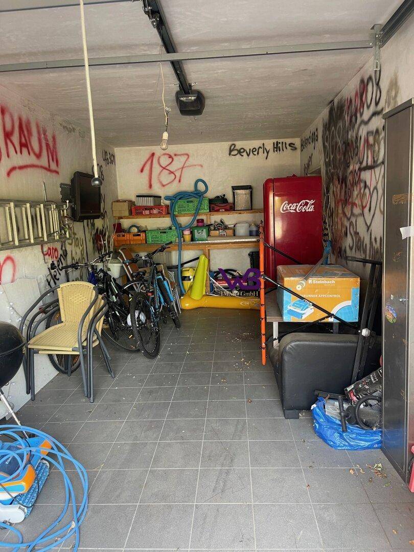 Geräumige Garage mit Fliesenboden, Stauraum und kreativen Wandbemalungen.