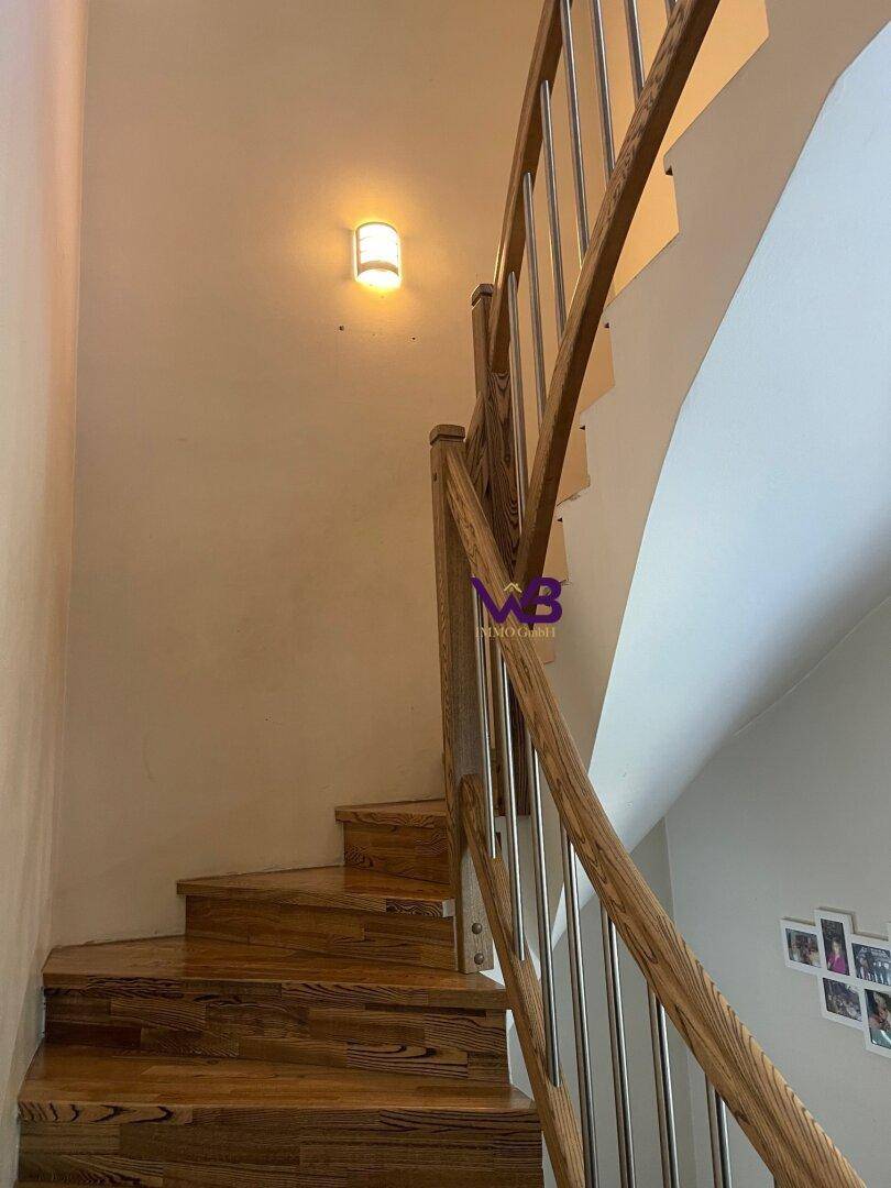 Holztreppe mit Metallgeländer führt in die obere Etage des Hauses.