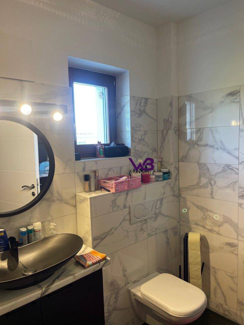 Modernes Gäste-WC mit Marmorfliesen, Wand-WC und stilvollem Waschbecken.