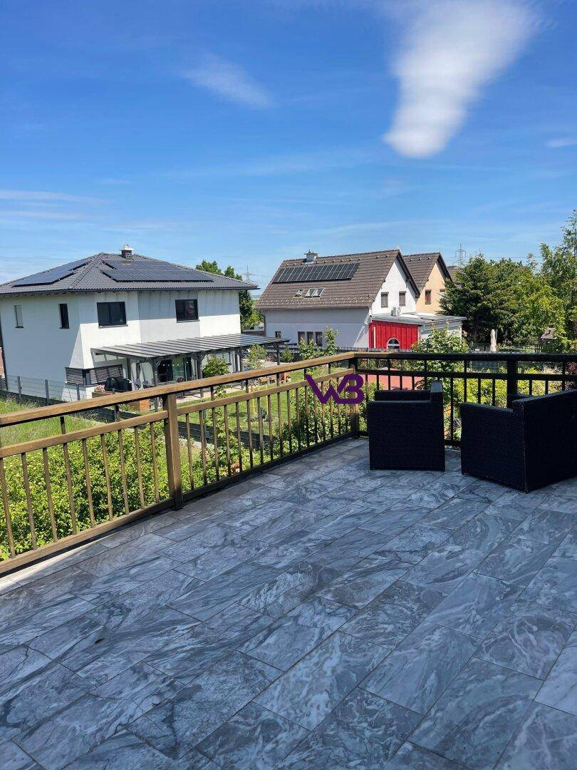 Großer Balkon mit Fliesenboden und Sitzgelegenheiten, bietet Blick auf die Nachbarschaft.