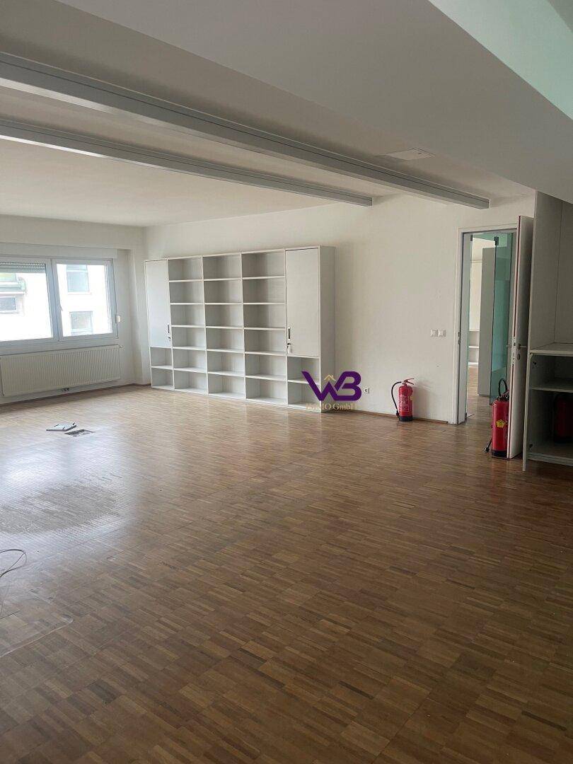 Heller, leerer Raum mit Holzparkettboden, weißen Wänden und eingebauten Regalsystemen.
