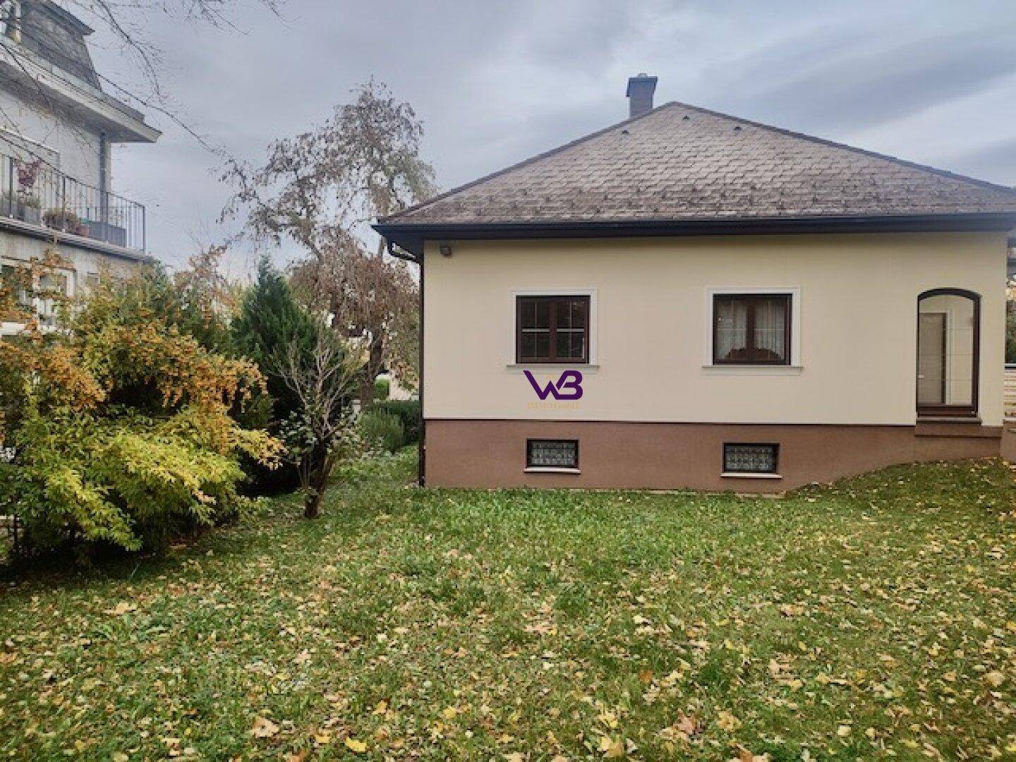 Rückseite des Hauses mit Garten, Rasenfläche und herbstlicher Bepflanzung.