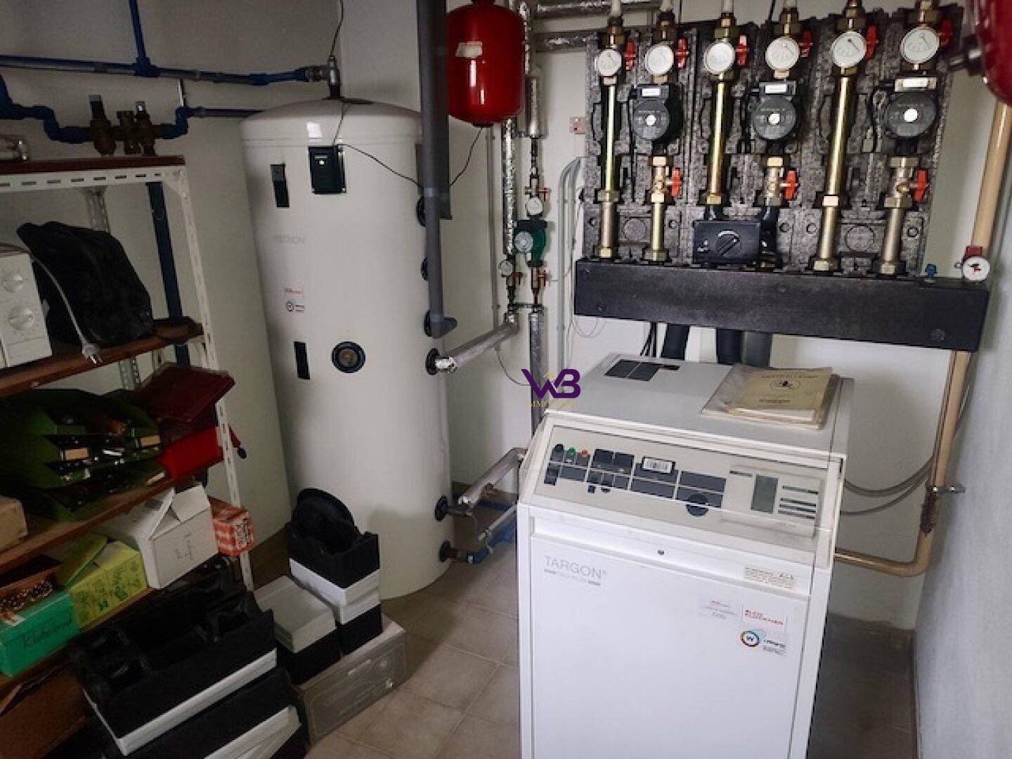 Heizraum mit Warmwasserspeicher und Heizungsverteiler, gut organisiert und funktional.