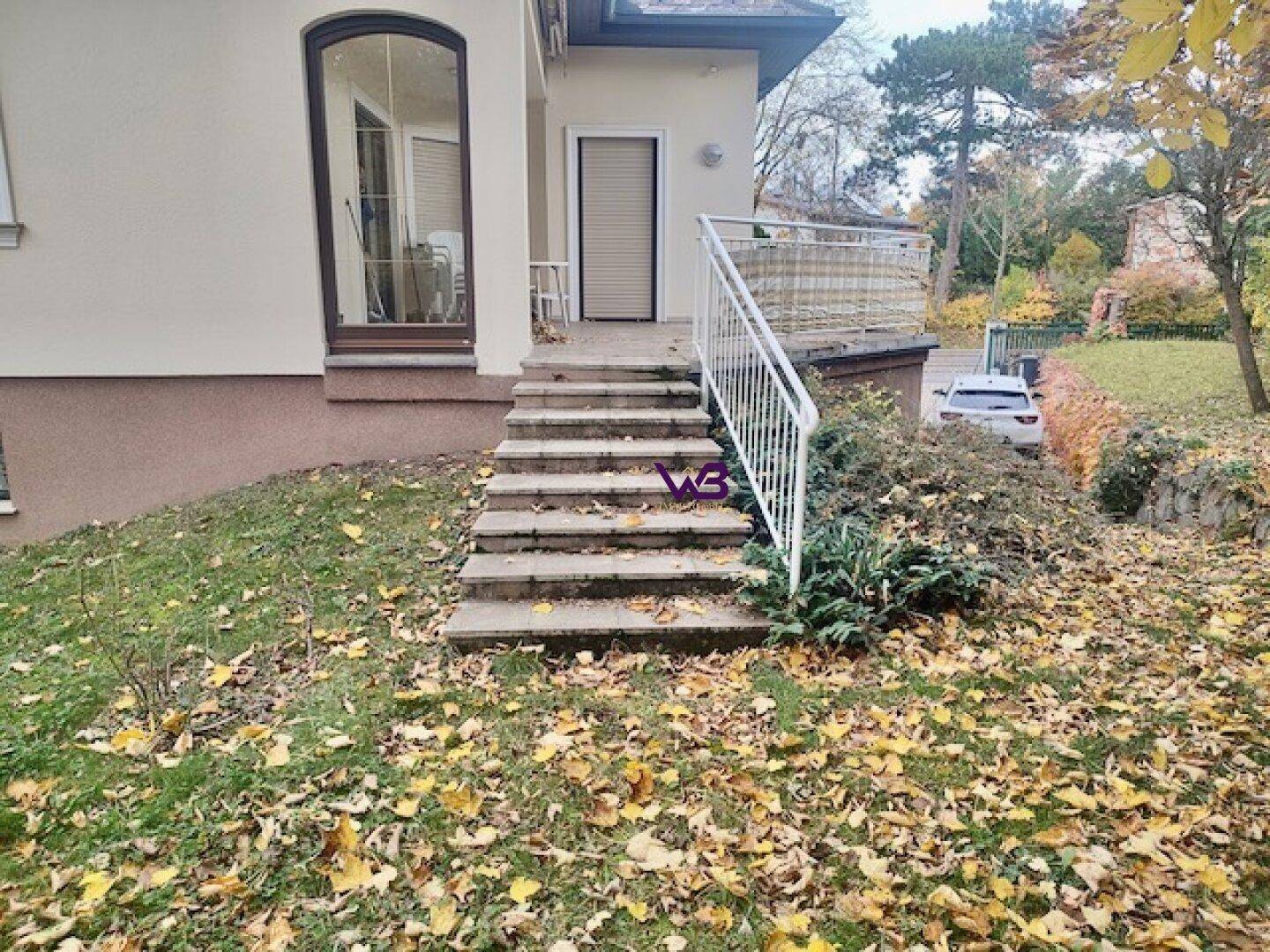 Treppe vom Haus in den Garten, umgeben von herbstlichem Laub und Grün.