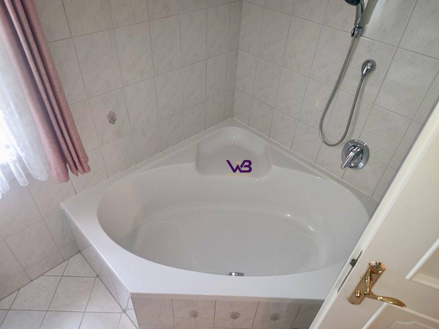 Badezimmer mit Eckbadewanne und hellen Fliesen an Wänden und Boden.