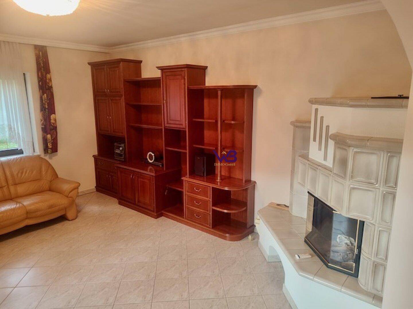 Wohnzimmer mit Kamin, Fliesenboden und traditionellen Holzmöbeln, die eine warme Atmosphäre schaffen.