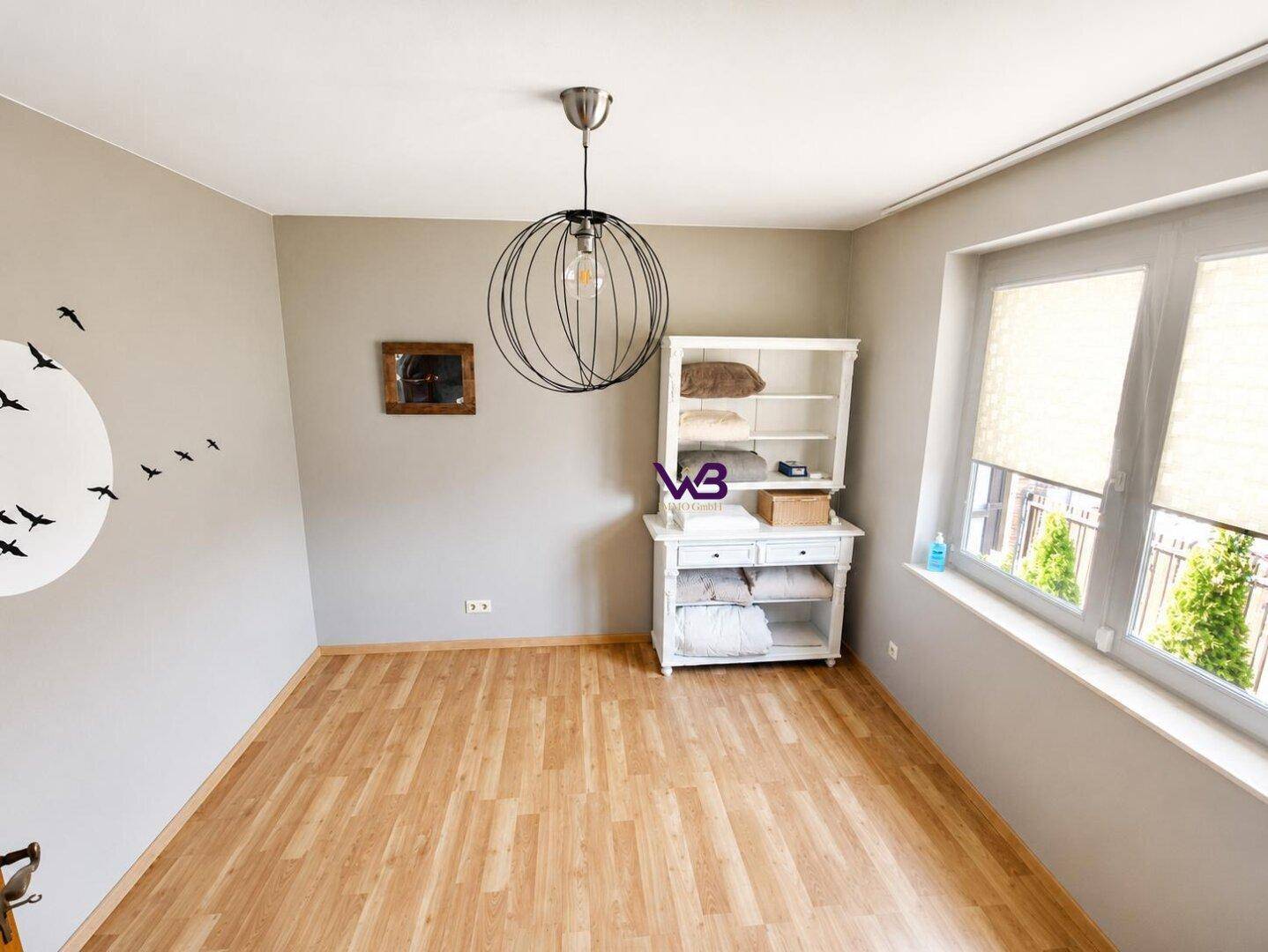 Helles Zimmer mit Holzboden und großem Fenster, ideal als Gästezimmer oder Arbeitsbereich nutzbar.