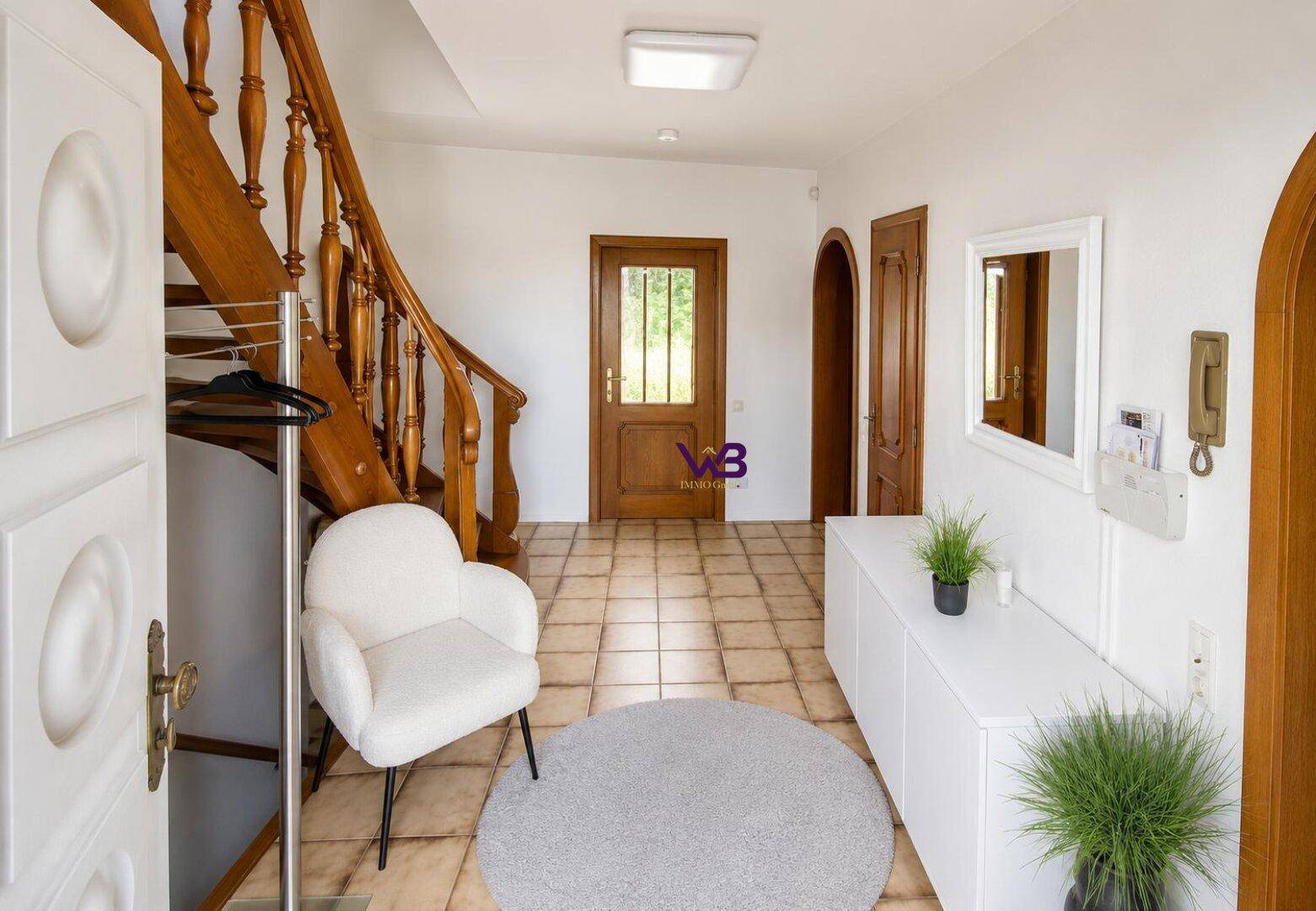 Heller Eingangsbereich mit Holztreppe, gefliestem Boden und Garderobe, einladend gestaltet.