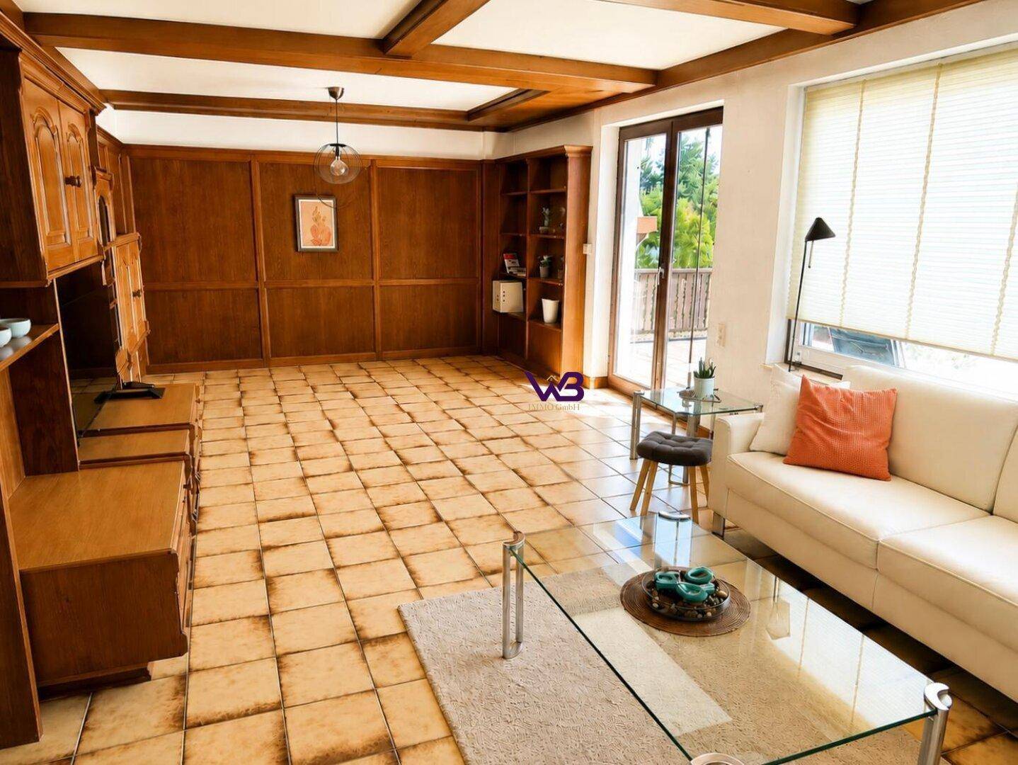 Großes Wohnzimmer mit Holztäfelung, gefliestem Boden und Zugang zur Terrasse, hell und geräumig.