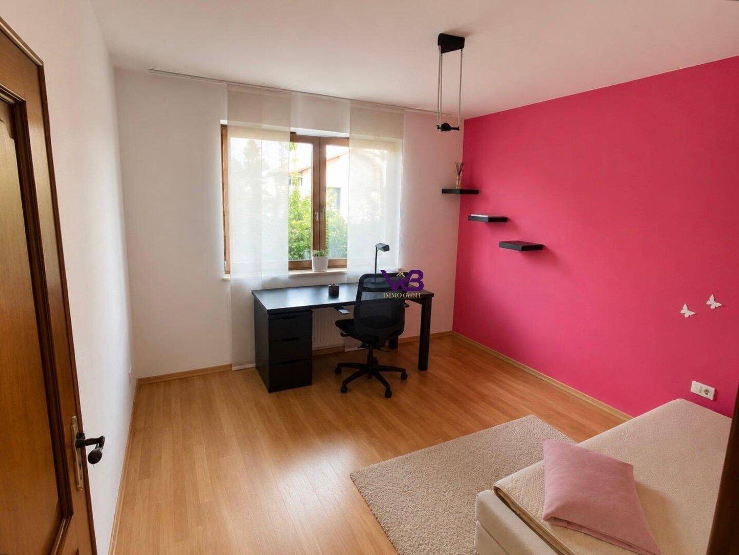 Freundliches Zimmer mit Holzboden, Schreibtisch und leuchtend pinker Wand, ideal für Kinder oder Büro.