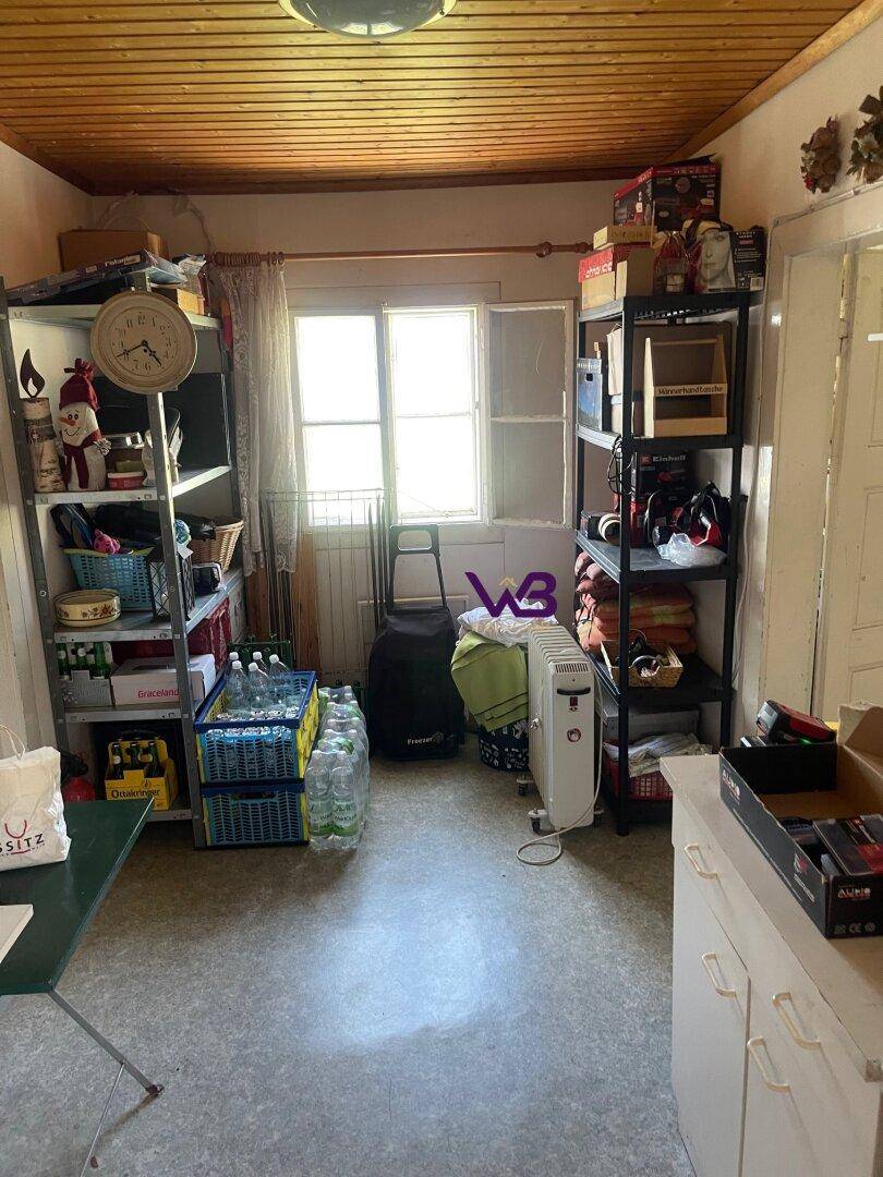 Funktionaler Abstellraum mit Metallregalen, vielen Lagerartikeln und einer Holzdecke.