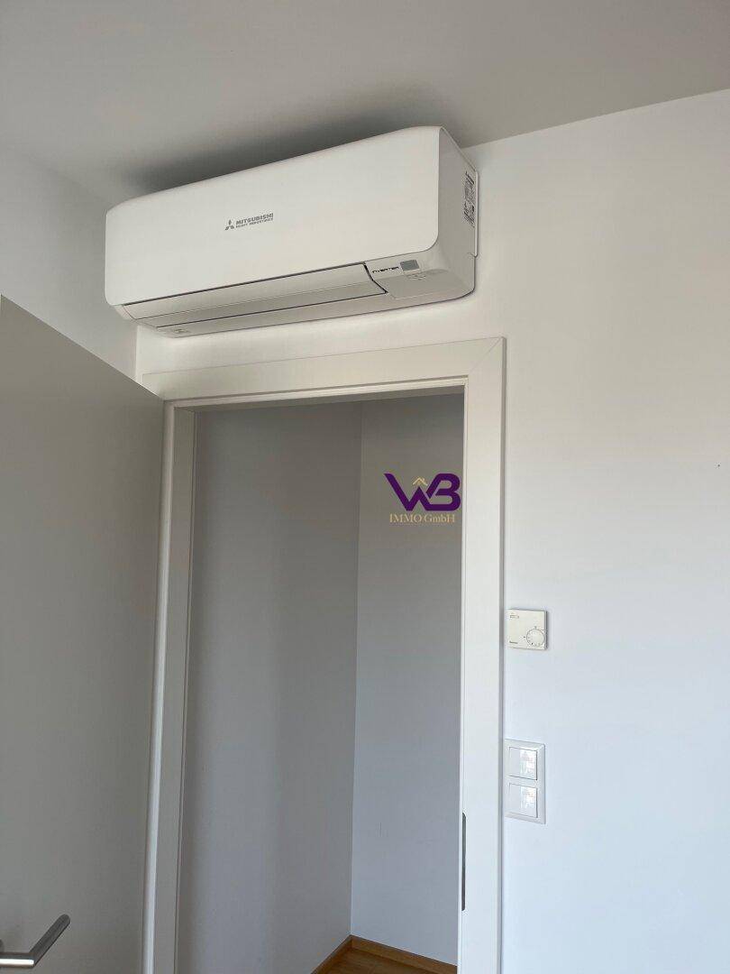 Flur mit Klimaanlage über der Tür und weiß gestrichenen Wänden.