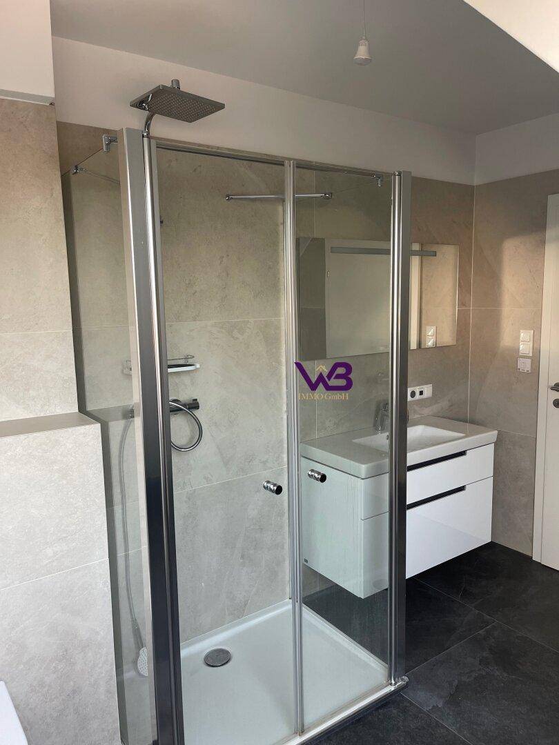 Duschkabine mit Glaswänden und modernem Waschbeckenunterschrank im Badezimmer.